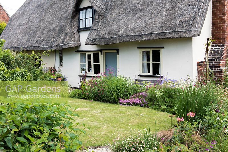 Caynton Cottage, une chaumière du XVIIe siècle, surplombe une pelouse bordée de vivaces.