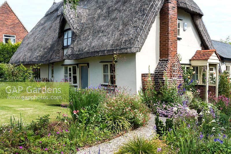 Caynton Cottage, une chaumière du XVIIe siècle, surplombe une pelouse et des sentiers bordés de vivaces.