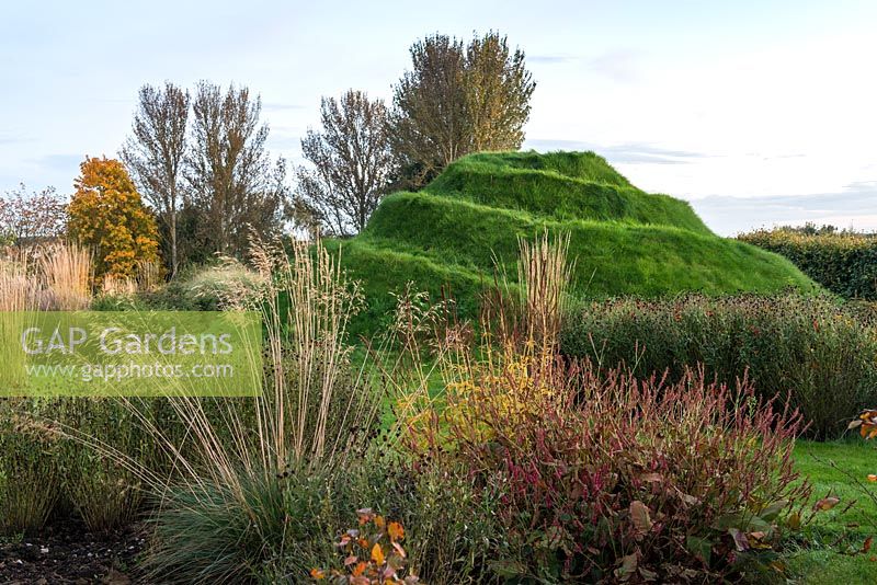 Mound, une plate-forme d'observation herbeuse, vue à travers des parterres de graminées ornementales et de vivaces.