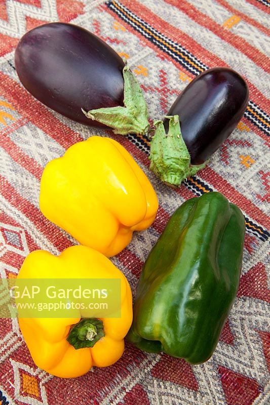 Légumes frais colorés - poivrons jaunes et verts aux aubergines sur une table couverte de kilim