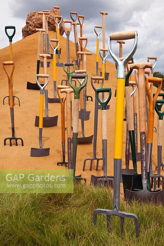 Jardin conceptuel avec des outils de jardin dans le sable au RHS Hampton Court Flower Show