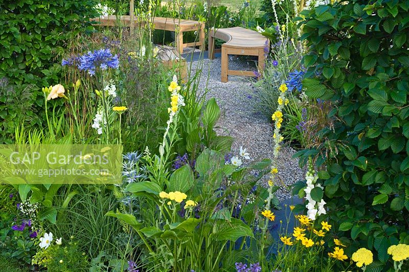 Jardin contemporain avec chemin de gravier et coin salon avec bancs en bois Designers: Catherine Chenery Barbara Harfleet