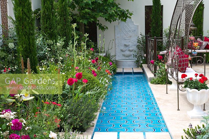 Un large ruisseau d'eau avec des parterres luxuriants à côté d'un coin salon dans le ministère turc de la Culture et du Tourisme: Garden of Paradise.