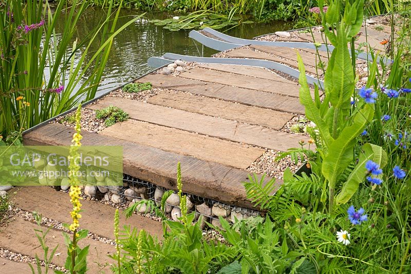 Le WWT Working Wetlands Garden, RHS Hampton Court Flower Show 2016. Designer Jeni Cairns. Passerelle sur le ruisseau