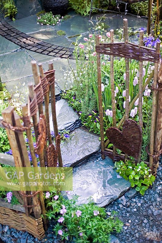 Romantique cour intérieure jardin avec pavage en pierre saule clôtures osier amour coeur ornements chalet d'été plantation pérenne