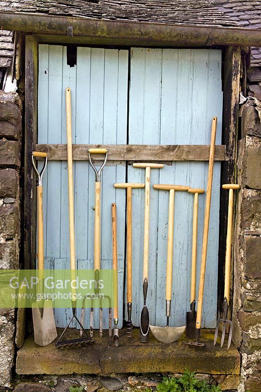 Ligne d'outils de jardin De Wit contre une porte de grange en bois bleu