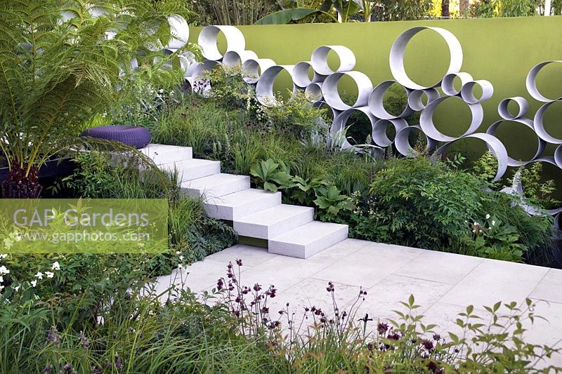 Cancer Research UK Garden Andy Sturgeon Chelsea Show Garden avec feuillage de fougère arborescente, plantation pérenne, mur d'anneaux en acier