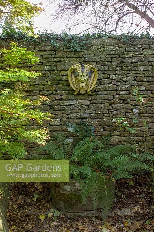 L'Abbey House, Malmesbury, Wiltshire, Royaume-Uni (Pollard). Automne dans un grand jardin, masques 'païens' comme ornement