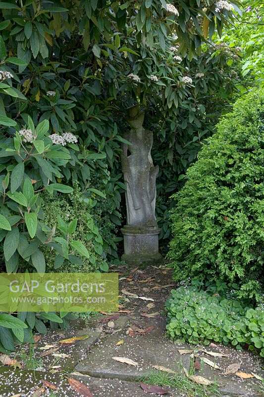 Barnsley House Gardens, Glos., Royaume-Uni. Ancien jardin de Rosemary Verey, statues cachées parmi les buissons en bordure de jardin