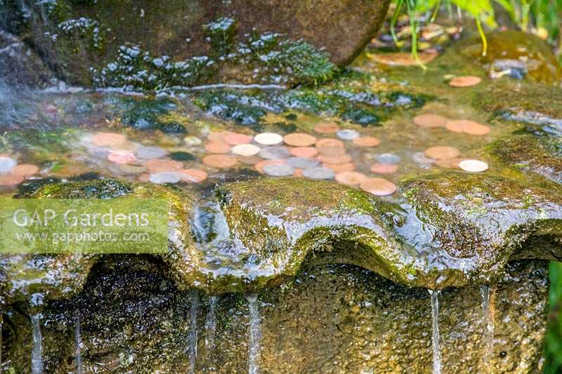 Barnsley House Gardens, Gloucestershire, Royaume-Uni. caractéristique de l'eau avec des pièces jetées pour la bonne chance