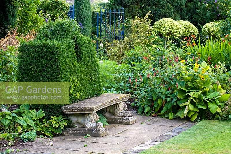 Barnsley House Gardens, Gloucestershire, Royaume-Uni. assise en pierre avec 'dossier' topiaire