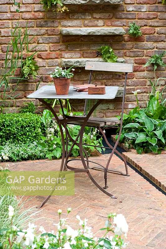Chelsea Flower Show, 2009. Jardin 'Jacob's Ladder' (des. Jeff Hewitt) table et chaise simples et élégantes dans un petit jardin avec un pavage en briques