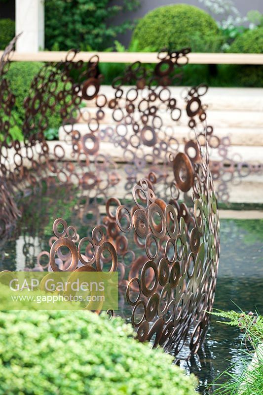 Sculpture en anneau de cuivre à côté de l'étang, Le Jardin MG, des. Andy Sturgeon.