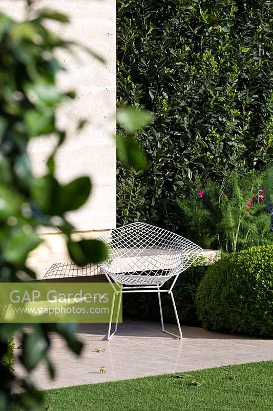 RHS Chelsea Flower Show 2014. The Telegraph Garden, designer Tommaso Del Buono. Élégante chaise en métal dans un jardin moderne.