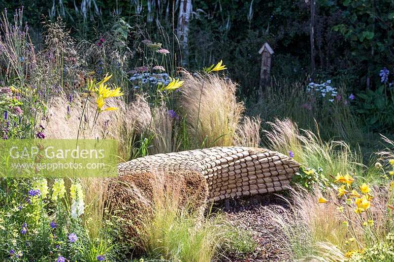 Hampton Court Flower Show 2014, le Jordans Garden, des. Selina Botham. banc de paille parmi les graminées et les vivaces naturalistes