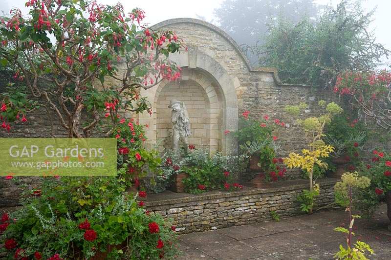 Hodges Barn, Gloucestershire, Royaume-Uni (Hornby) patio avec mur de pierre des Cotswolds et plantes semi-rustiques