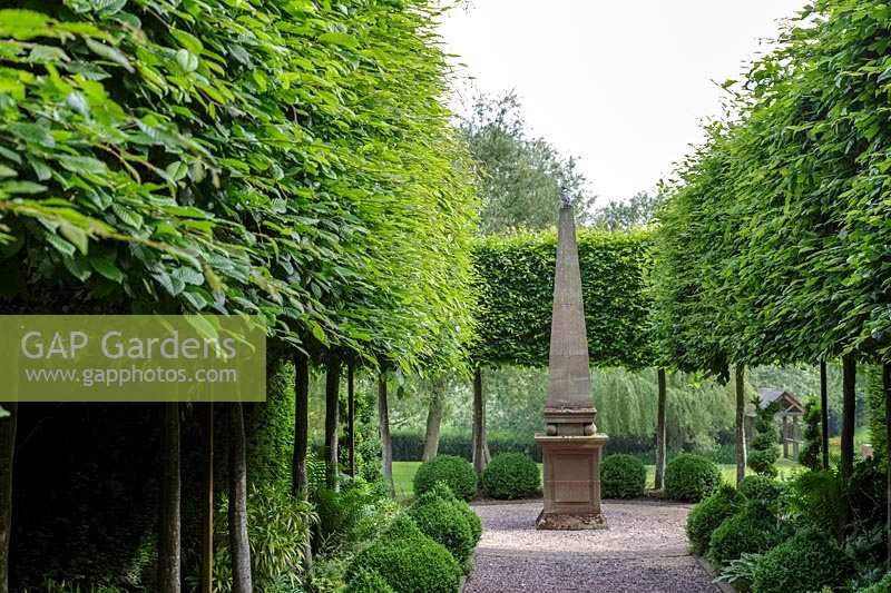 Mitton Manor, Staffordshire. Point focal de l'obélisque de pierre dans le jardin à la française