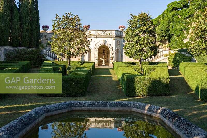 Villa La Foce, Toscane, Italie. Grand jardin avec couverture topiaire coupée et vue sur la campagne toscane, étang et Magnolia grandiflora sur la terrasse inférieure