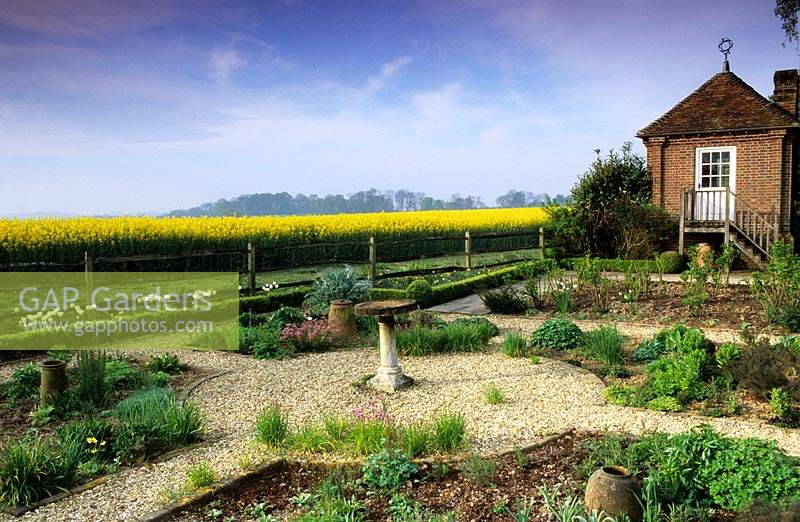 Jardin privé chemins de gravier Sussex avec bain d'oiseaux point focal au printemps gazebo vue du champ de colza