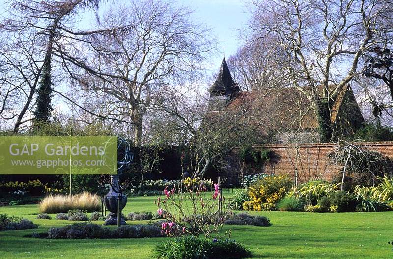 Jardin clos de Rymans Sussex avec pelouse au printemps avec parterres de l'île et sphère armillaire
