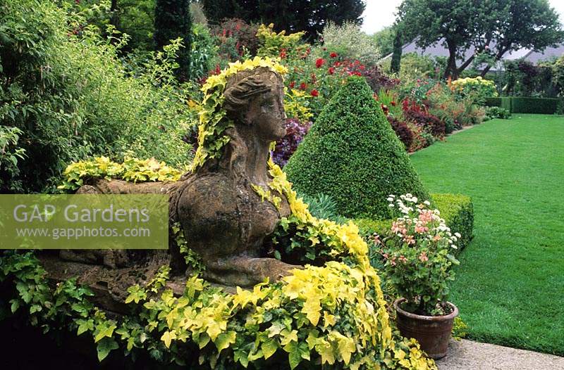 Le jardin Dillon Dublin Irlande grande ville banlieue jardin statue de Sphinx en pierre recouverte d'hélice Hedera Buttercup et pyramide