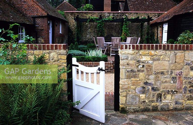 Cour inférieure Surrey design Transform Landscapes Courtyard patio garden avec mur de pierre et portail été septembre
