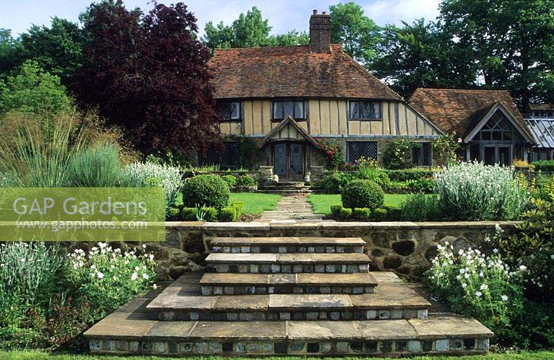 Shalford House Surrey design Sally Court marches en pierre menant à une pelouse surélevée avec vue sur maison