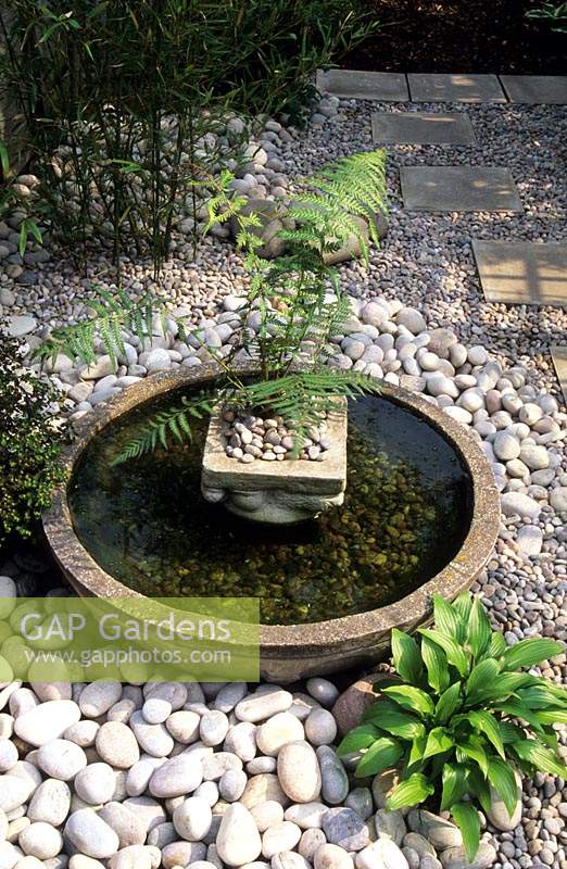 Un bol peu profond présente un style japonais dans un petit jardin de ville entouré de jolies pierres blanches et de paillis de galets
