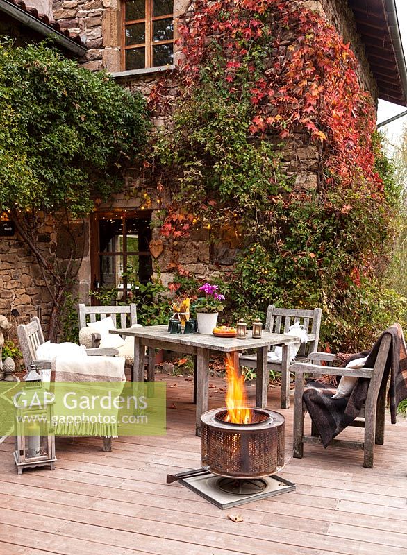 Table de jardin, chaises et panier à feu sur la terrasse du jardin mis en place pour la soirée, Le Mas de Béty, France.