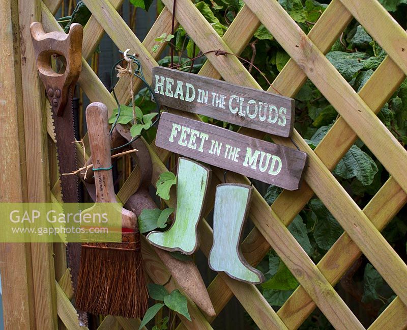 Un signe de jardin humoristique suspendu à un panneau en bois.
