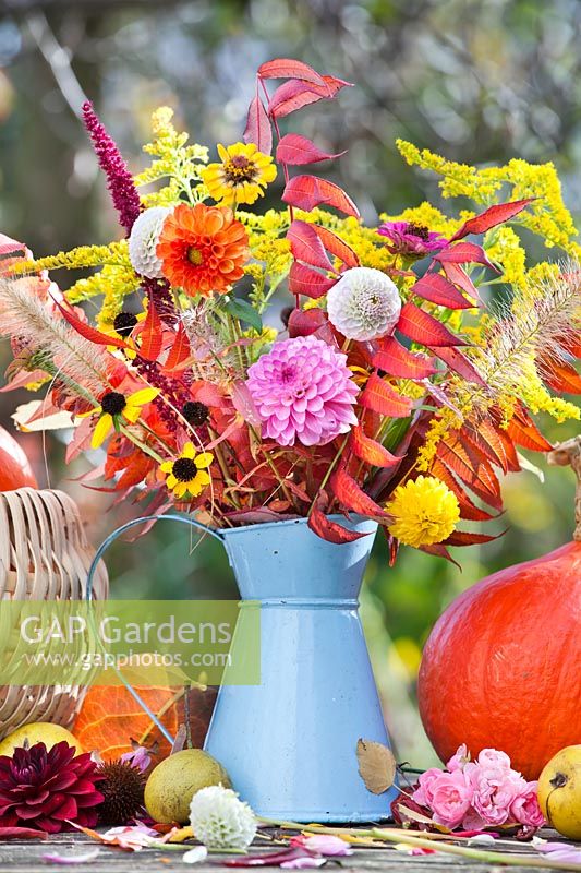 Cruche bleue remplie de fleurs et de feuillage automnaux - Feuilles de Dahlia, Rudbeckia, Pennisetum, Amaranthus et Rhus.