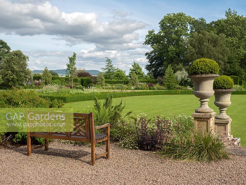Le banc est placé sur la terrasse en gravier et donne une vue sur le jardin à la française vers les collines environnantes du Herefordshire.