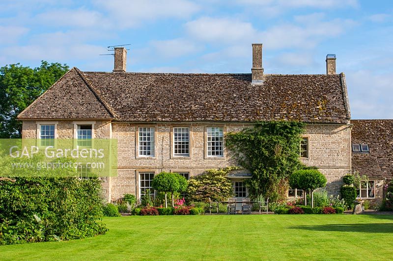Vue sur maison d'époque anglaise avec étendue de pelouse.