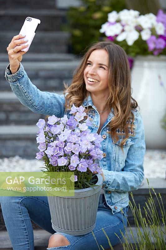 Femme prenant selfie en plein air avec pot de Campanula - campanules