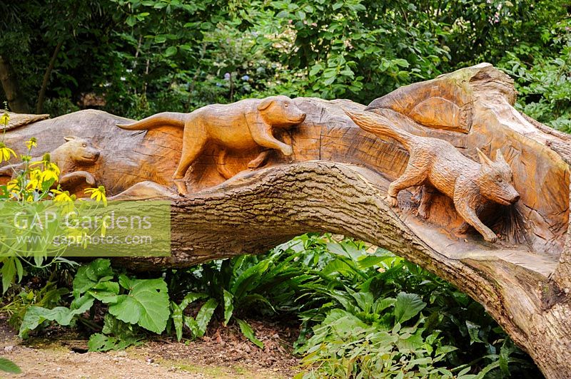 Chêne abattu sculpté d'une scène de chasse sur un côté, par le sculpteur à la tronçonneuse Matthew Crabb. Jardins subtropicaux d'Abbotsbury, Abbotsbury, Dorset, UK.