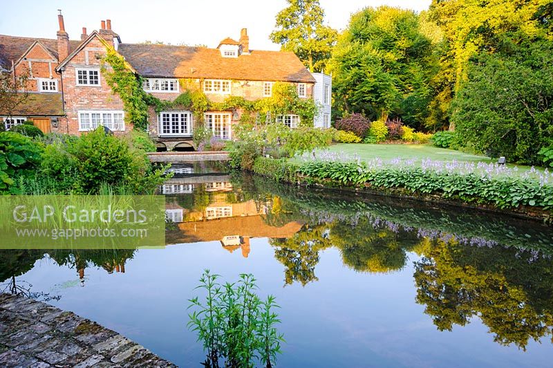 Les canaux d'eau autrefois utilisés pour conduire le moulin reflètent maintenant la maison et les jardins environnants. Dipley Mill, Hartley Wintney, Hants, Royaume-Uni.