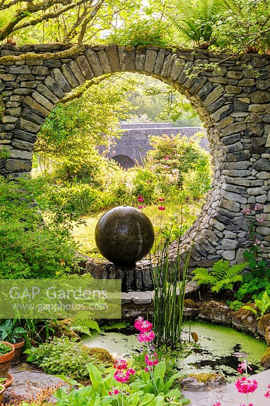 Fenêtre de la lune dans un mur en pierre avec fontaine en béton coulé et piscine avec Equisetum hyemale. Fanore, Irlande