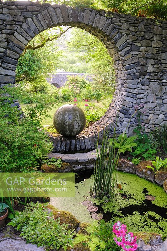 Fenêtre de la lune dans un mur en pierre avec fontaine en béton coulé et piscine circulaire. Fanore, Irlande