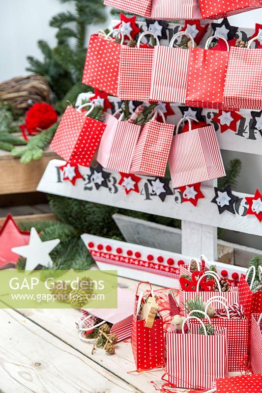 Sapin de Noël en palette de l'Avent décoré de sacs en papier remplis de cadeaux festifs dans un cadre festif moderne