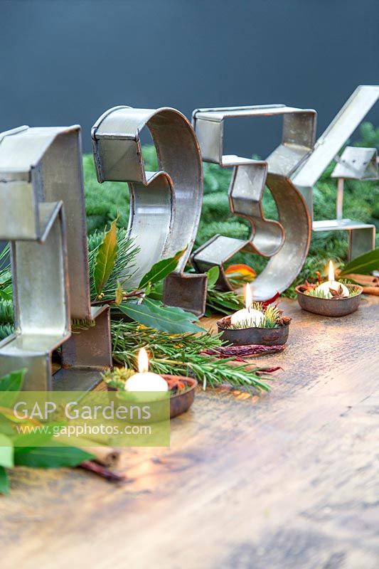 Décoration de table de l'Avent avec de grandes moules à gâteaux en métal et de petites bougies blanches