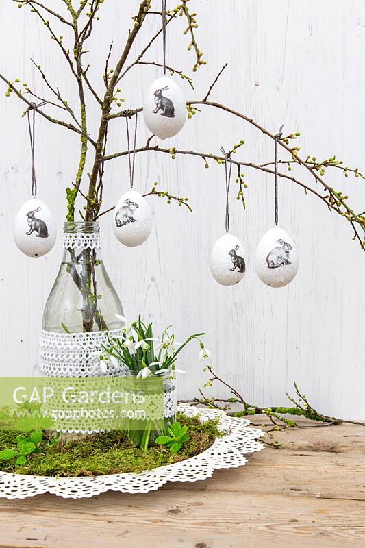 Oeufs de Pâques à suspendre sur des branches, perce-neige et vases décorés de dentelle