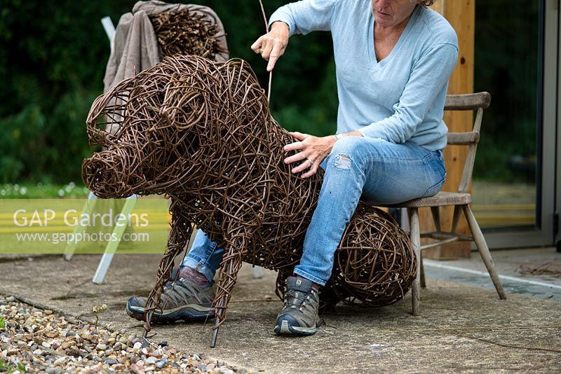Helen Colletta par son atelier travaillant sur une sculpture de cochon de saule. Saule des Wakelins, Suffolk