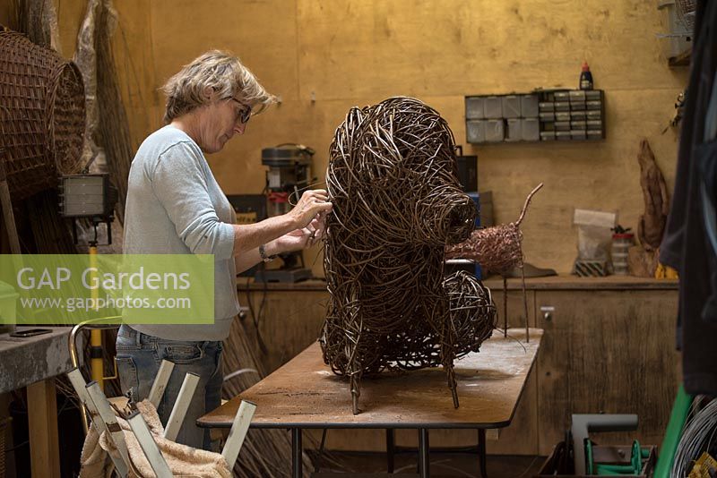 Helen Colletta dans son atelier travaillant sur une sculpture de cochon de saule. Saule des Wakelins, Suffolk