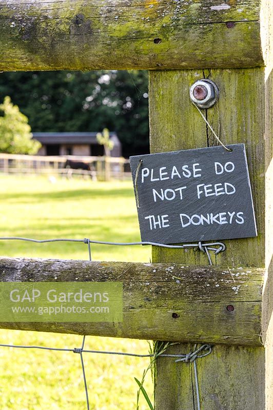 Panneau demandant aux visiteurs de ne pas nourrir les ânes sur la clôture de leur enclos.