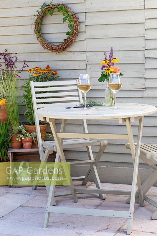 Table et chaises de jardin en bois peint avec verres à vin et composition florale