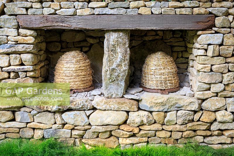 Fûts d'abeilles de paille fixés dans le mur de pierres sèches - Le jardin Warner Edwards, une représentation de Falls Farm dans la campagne du Northamptonshire, commanditaire: Warner Edwards, RHS Chelsea Flower Show, 2018.