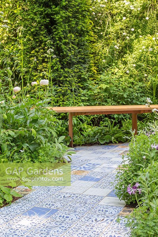 Chemin de carreaux de céramique par Sue Ridge, entouré de plantations menant à un banc en bois. Le jardin de l'épilepsie des esprits brodés. Sponsor: Embroidered Minds, RHS Chelsea Flower Show, 2018.