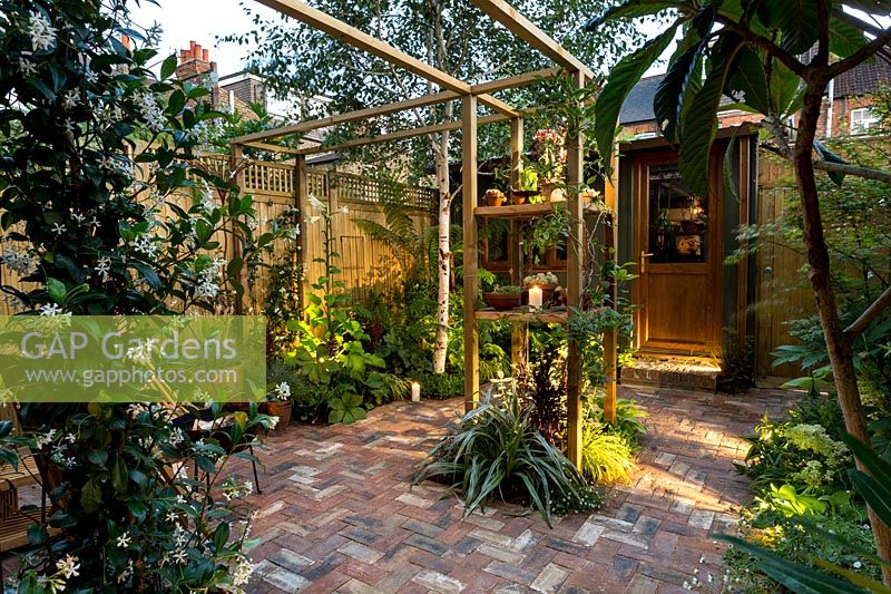 Petit jardin patio londonien avec pergola centrale et spots.