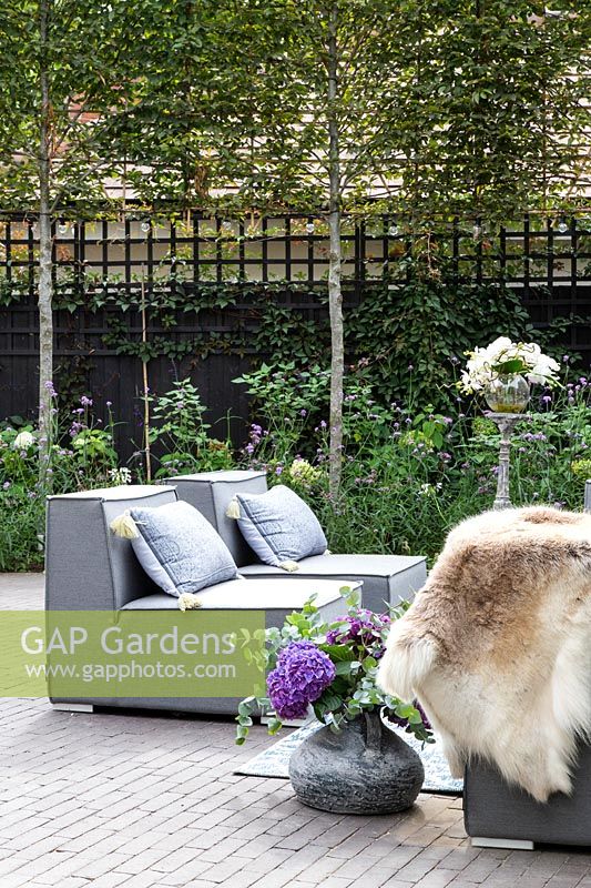 Arrangement de chaise d'extérieur gris avec coussins, peau, tables, boissons et compositions florales jaunes