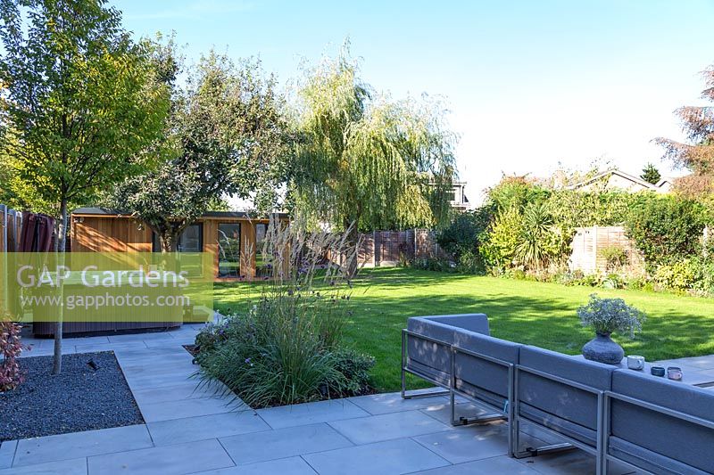 Vue sur jardin de banlieue moderne avec mobilier de salon, bain à remous et arbres matures